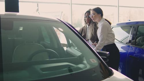 Customers Exploring Features of a New Car Model at an Auto Dealership During Daylight Hours