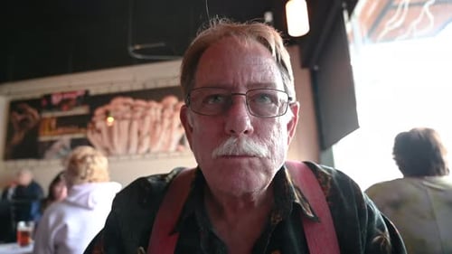 Mature Caucasian man bites into big sandwich at a restaurant.
