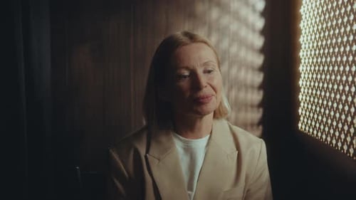 Senior Woman Performing Sacrament of Penance in Confessional Booth