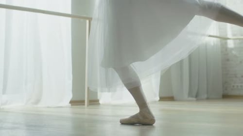 Close-up Shot of Ballerina's Legs. She Dances on Her Pointe Ballet Shoes. She's Wearing White Tutu