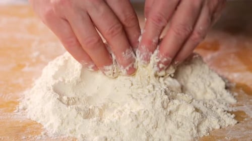 Hands Mixing Flour and Eggs for Dough