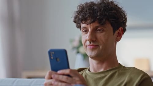 Man with Curly Hair Uses Smart Phone