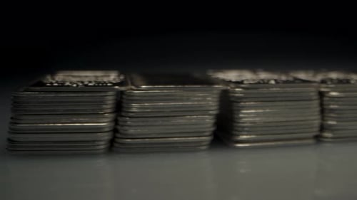 Cinematic of many stacks of silver bars lit by a spotlight in a dark room