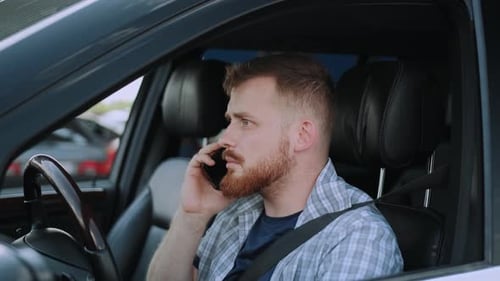 Adult Man Anxiously Talking on Phone in Car