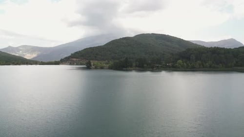 Aerial footage over the lake in the mountains, sunny, green landscape