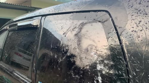 Water Cleans a Black Car Exterior