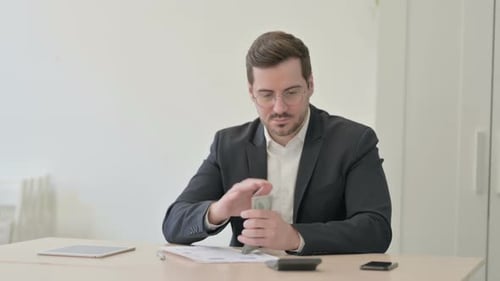 Man Counting Money, Using Calculator, Writing in Office