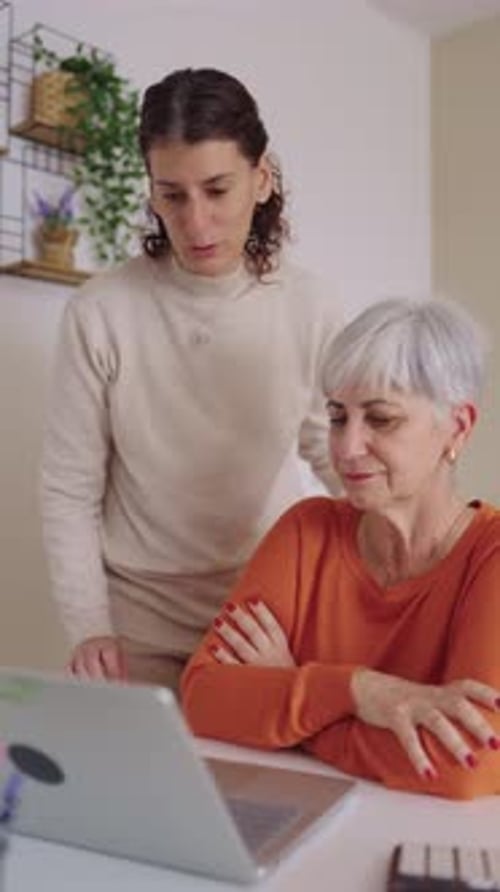 Woman Helping Senior Woman Use Laptop At Home
