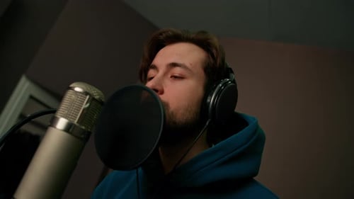 singer with headphones and microphone emotionally recording a new song in a professional studio