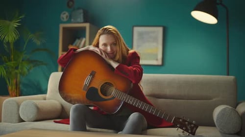 Mujer sentada en el sofá con una guitarra