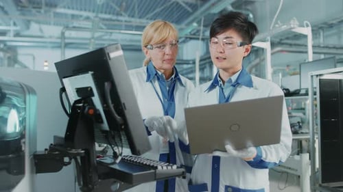 On High Tech Factory Asian Engineer Talks with Female Supervisor, Use Computer for Programming Pick