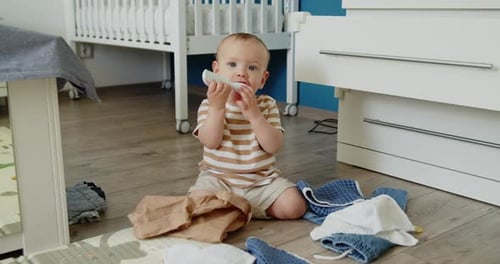 Cute Teething Baby Gnawing Comb Sitting on a Bedroom Floor