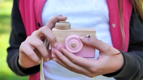 Toy Wooden Camera in the Hands of a Teenage Girl