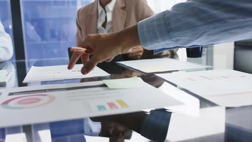 Pointing at financial charts, business team discussing project in office meeting