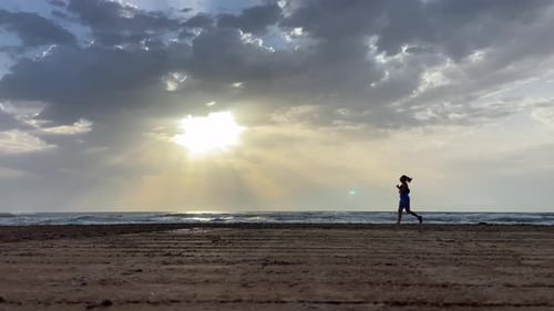 Athletic young girl running along the beach in the early morning