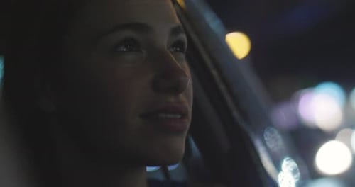 In the night, a beautiful woman puts the traveling head out the car window to admire the view and