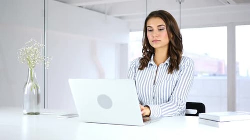Serious Woman Working On Laptop in Office