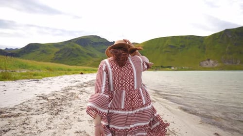 Woman Walking on Scenic Beach with Mountains