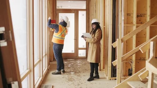 Homebuilder and Inspector with Tape Measure at Home Construction Site Adult