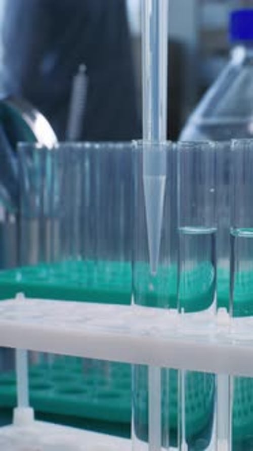 Close Up of Scientist Pouring Blue Into Test Tubes with Pipette