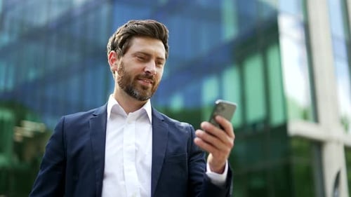 Smiling Businessman Using Smartphone Outside Office Building
