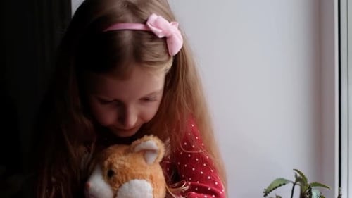 Girl Holds Stuffed Animal and Looks out Window