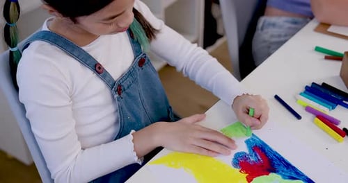 Child Drawing with Crayons at White Desk