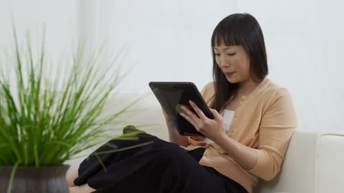 Relaxed woman using tablet while sitting on sofa