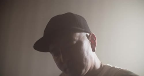 Male Composer Tuning Bass Guitar and Playing in Music Studio