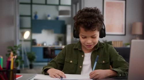 Child Doing Schoolwork With Headphones and Laptop