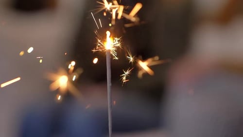 Close up sparkler glowing heat sparks at part event bokeh background celebrations.