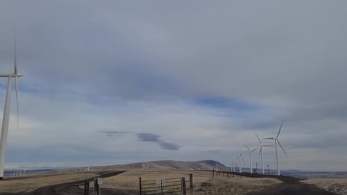 An einem bewölkten Tag an einem Windpark vorbeifahren.