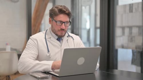 Junger Arzt tippt in der Klinik auf Laptop