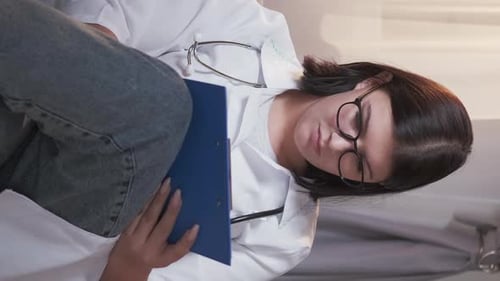 Medical Professional Taking Notes on Examination Table
