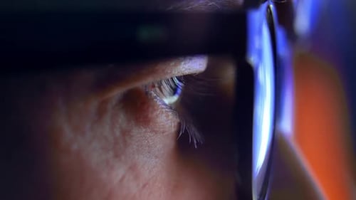 Homme adulte, yeux dans des lunettes, regardant un écran d'ordinateur et une vidéo sur Internet en ligne