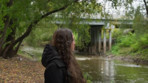 Woman Strolling By River Side Profile of Woman Near River Under Cloudy Sky Reflective Woman Walking