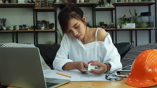 Female Architect Or Engineer use Vernier Caliper to measure the model house. Architectural Concept.