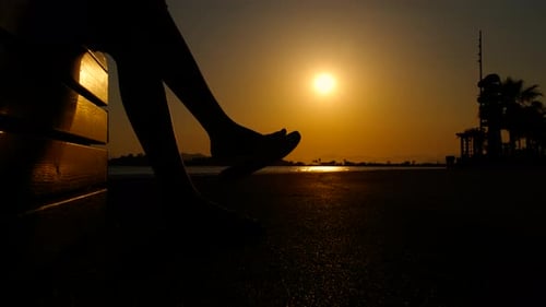 Woman Silhouetted on Bench at Sunrise