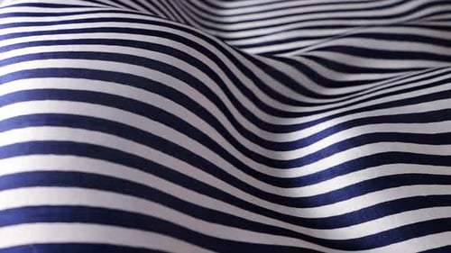 Close up of blue and white striped natural silk fabric waving in the wind.