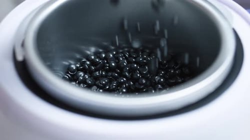 Melting Black Hard Wax Beans in Professional Warmer Ready for Precise Body Hair Removal Process at