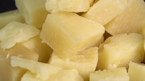 Les morceaux de parmesan tournent sur fond noir. Fromage affiné à pâte ferme et aromatique. Traditionnel