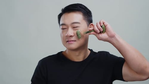 Young Man Using Facial Roller for Beauty Treatment