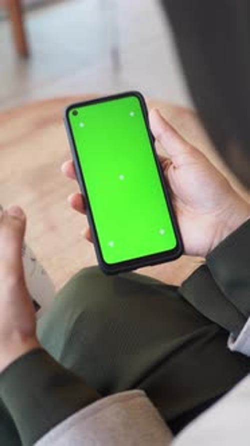 Holding a Smartphone with Green Screen at a Cafe