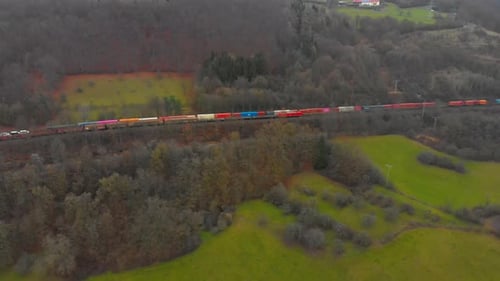 drone flight over a freight train transporting cargo through countryside