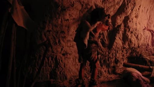 Caveman Creating Petroglyphs in Cave with Crude Tools