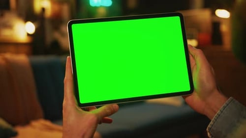 Close Up Hands Man Holding and Tapping on a Tablet Computer with a Horizontal Green Screen Mock Up