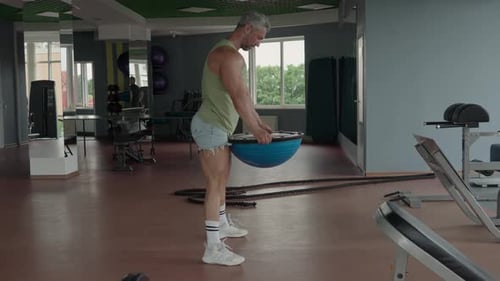 Man Doing Burpee Exercise in Fitness Gym with Balance Trainer
