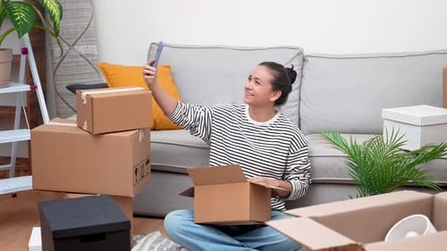 Woman Video Chats While Unpacking Moving Boxes