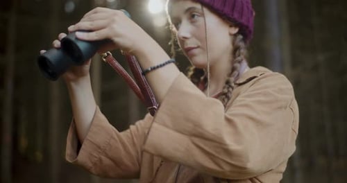 Female Explorer Observing Through Binoculars in Forest