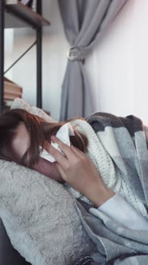 Woman Covered in Blanket Holding Tissue to Face